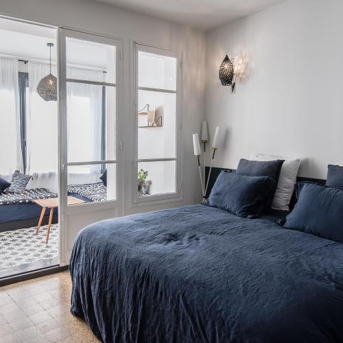 a bedroom with a blue bed and a balcony at Maison Volver in Arles