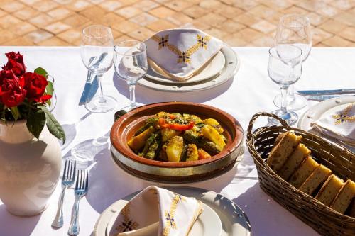 a table with a bowl of food and plates and wine glasses at Kasbah Caracalla in Aghmat