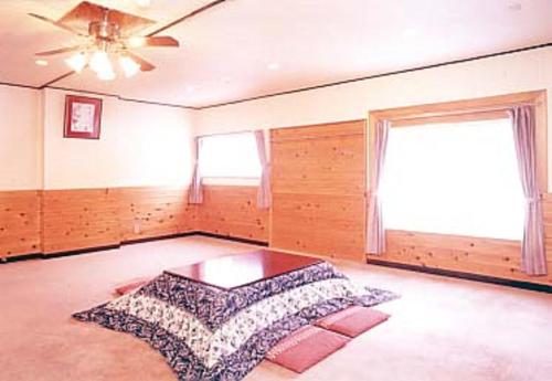 a large room with a bed and a ceiling fan at Pension Noah in Yuzawa