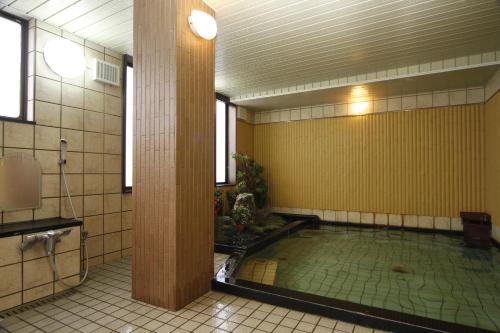 a bathroom with a swimming pool in a room with a pillar at Yodoya in Toyooka