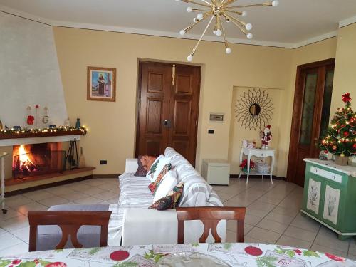 a living room with a white couch and a fireplace at Via del Fusato 13 Casa Carla in Chiusi della Verna
