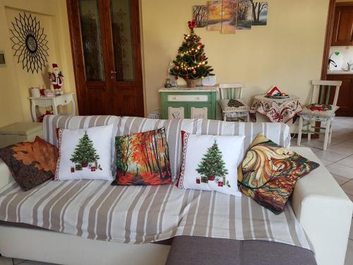 a living room with a white couch with christmas pillows at Via del Fusato 13 Casa Carla in Chiusi della Verna