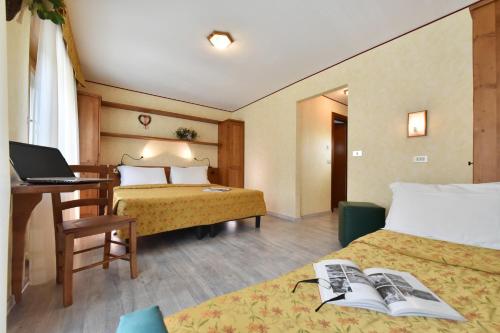 Habitación de hotel con 2 camas y escritorio con ordenador portátil. en Hotel Bijou, en Valtournenche