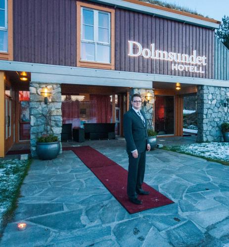 a man in a suit standing in front of a hotel at Dolmsundet Hotell Hitra in Melandsjøen