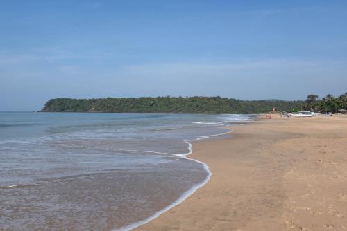 a beach with people walking on the sand and water at Agonda Paradise in Agonda