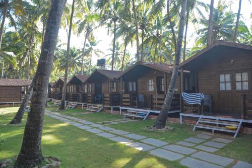 a row of cottages next to palm trees at Agonda Paradise in Agonda