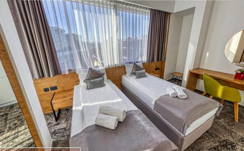 una camera d'albergo con due letti, una scrivania e una finestra di Orange Hotel a Sarajevo