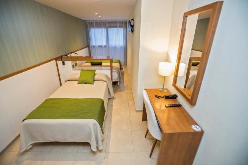 Habitación con 2 camas, escritorio y espejo. en Hotel Teruel, en Vinarós