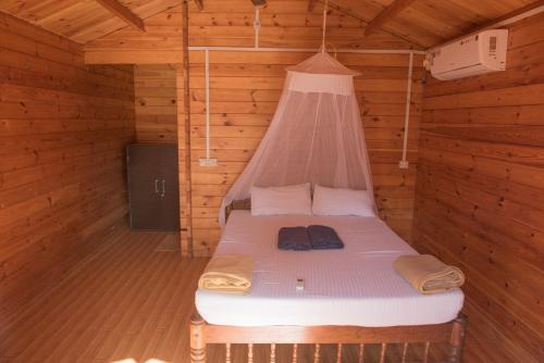 a bed in a wooden cabin with a net at Agonda Paradise in Agonda