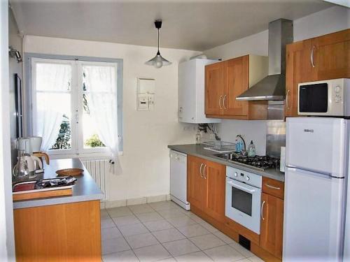 een keuken met houten kasten en een witte koelkast bij Ty Lisa - Spacieuse maison de village paisible proche ville et plages - 5 chambres - Kermorvan in Quiberon