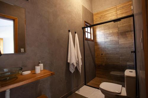a bathroom with a toilet and a glass shower at EcoVilla Las Mareas in Maresias