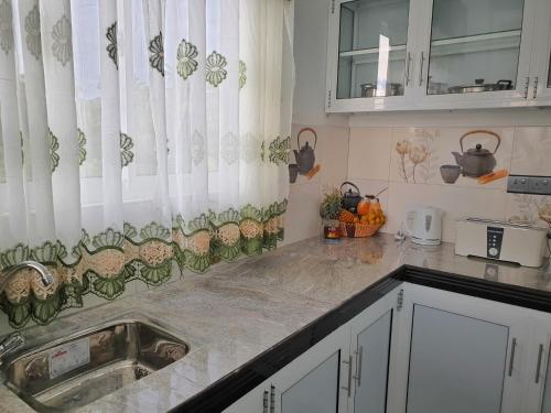 a kitchen with white curtains and a sink at Indika's Apartment in Hikkaduwa