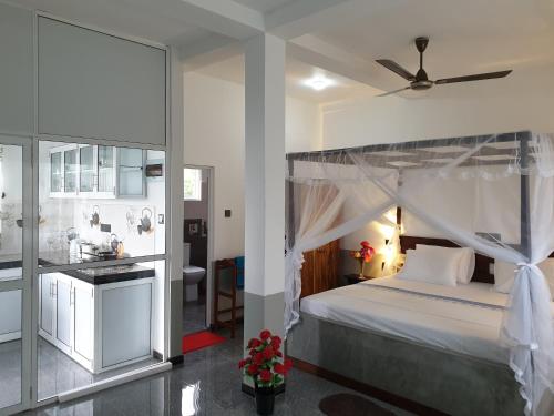 a bedroom with a canopy bed and a kitchen at Indika's Apartment in Hikkaduwa