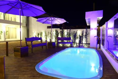 特拉曼達伊的住宿－Morada da Plataforma Tramandaí，一个带紫色遮阳伞和桌椅的游泳池