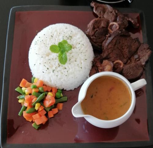 a plate with rice and a bowl of soup and vegetables at Niilo's Guesthouse in Rundu