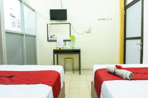 two beds in a room with a desk and a mirror at RedDoorz @ Gatot Subroto Ende in Ende