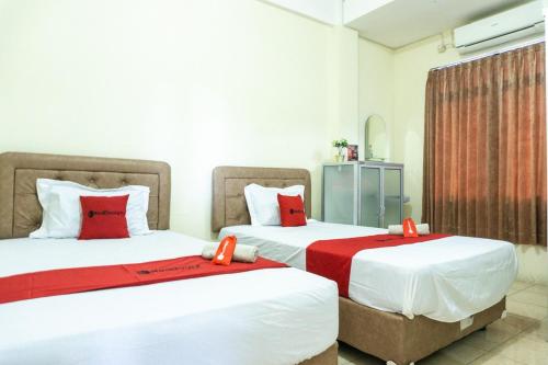 2 Betten in einem Hotelzimmer mit roten Kissen in der Unterkunft RedDoorz @ Gatot Subroto Ende in Ende