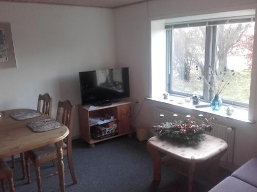 a living room with a table and a television and a table and chairs at Lindholt in Fjerritslev
