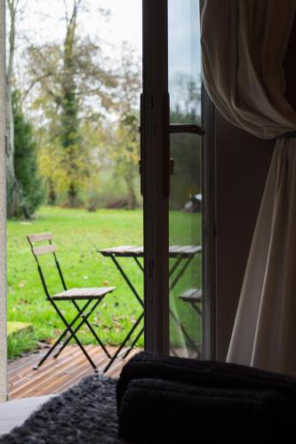 a view of a patio with a table and chairs through a door at Le Brame - Chambres d'Hôtes in Avilly-Saint-Léonard