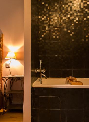 a bathroom with a bath tub with a lamp and a table at Le Brame - Chambres d'Hôtes in Avilly-Saint-Léonard