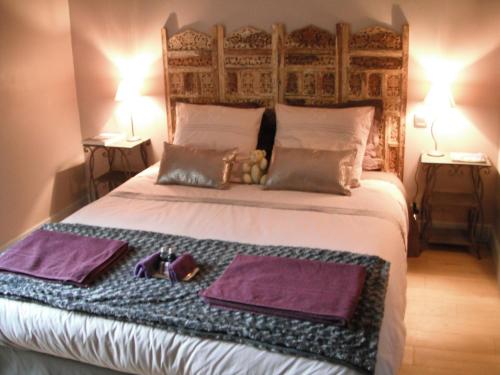 a bedroom with a bed with two purple towels and two lamps at Le Brame - Chambres d'Hôtes in Avilly-Saint-Léonard