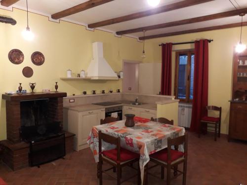 uma cozinha com uma mesa e uma lareira em Relax nel tufo em Pitigliano