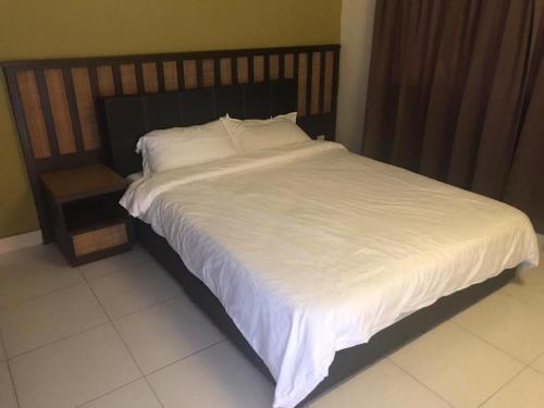 1 cama grande con sábanas blancas y cabecero de madera en Gold coast Morib apartment en Banting