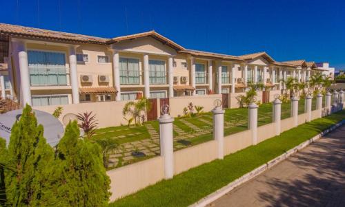 a long white fence with trees in front of a building at FLAT RESID MONT CARMELO in Porto Seguro