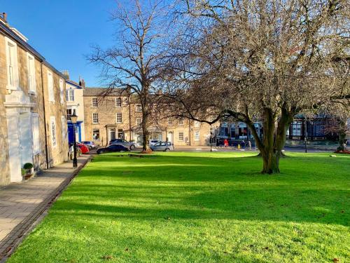 a grassy area with a tree in front of a building at The Old Toffee Works, Montpellier Quarter, Next to Pump Rooms FREE PARKING in Harrogate