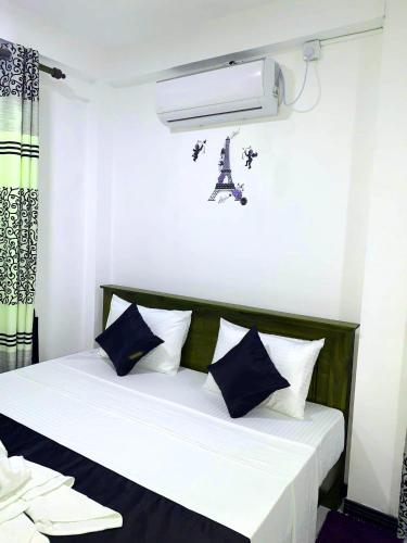a bedroom with a bed with blue and white pillows at Sura Homestay Kandy in Kandy