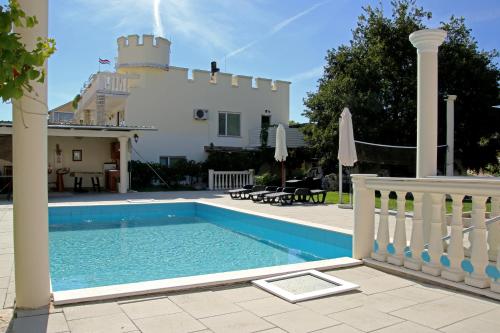 a villa with a swimming pool in front of a house at Apartments Kata in Šibenik