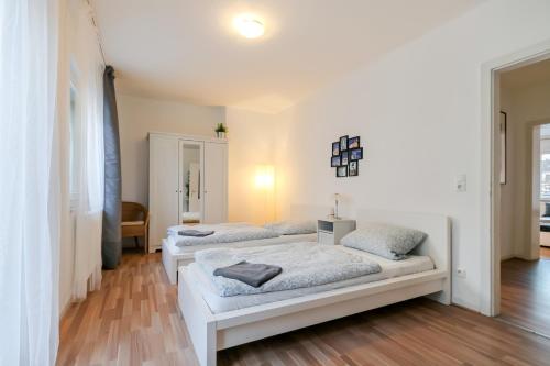 2 Betten in einem Zimmer mit weißen Wänden und Holzböden in der Unterkunft Fewo CityLife Köln-Innenstadt in Köln