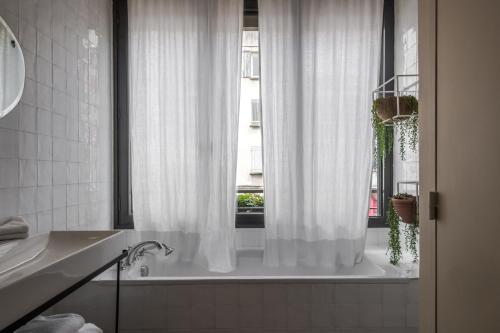 a bathroom with a white shower curtain and a window at Maison Volver in Arles