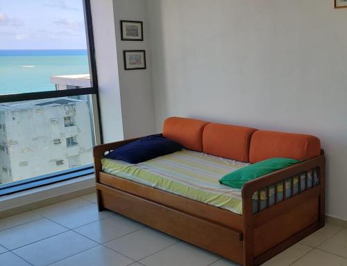 um sofá sentado num quarto com uma janela em Apartamento mobiliado e confortável em candeias no Recife