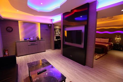 a living room with a bed and a tv in a room at Yosemite Motel - Taiyuan Branch in Taichung