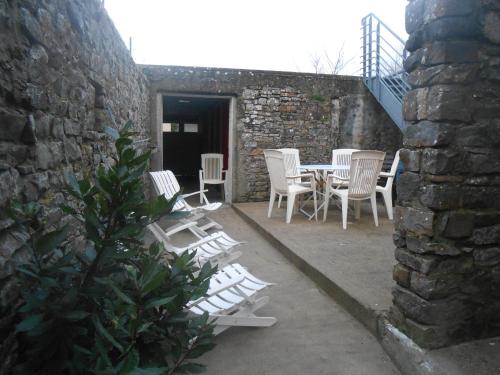 a patio with white chairs and a table and a building at Maison centre bourg Port-Bail in Portbail