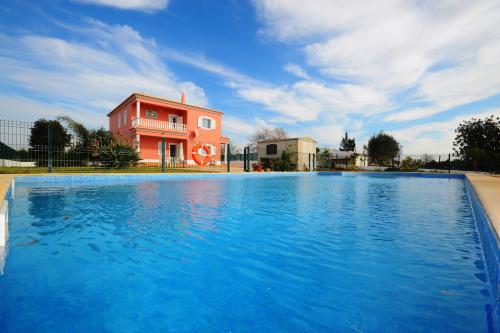 a large swimming pool in front of a pink building at Villa Casa das Amendoeiras in Alcantarilha