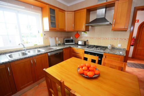 a kitchen with a table with a bowl of oranges on it at Villa Casa das Amendoeiras in Alcantarilha