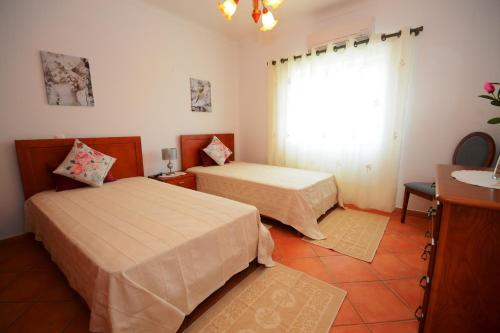 a bedroom with two beds and a sink and a window at Villa Casa das Amendoeiras in Alcantarilha