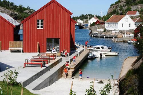 Une grange rouge et un port de plaisance avec des enfants jouant sur le quai dans l'établissement Verftet i Ny-Hellesund, à Søgne