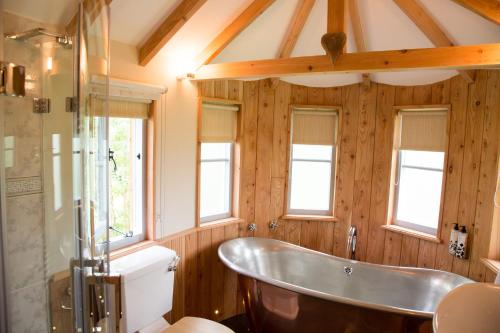 a bathroom with a tub and a toilet and windows at Fox & Hounds Country Hotel in Chulmleigh