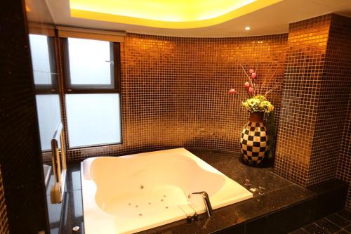 a bathroom with a sink and a vase with flowers at Yosemite Motel - Taiyuan Branch in Taichung