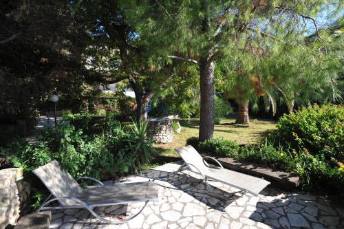 two chairs and a bench in a park at Villa Theodora View Apartments Erato in Agios Georgios Pagon