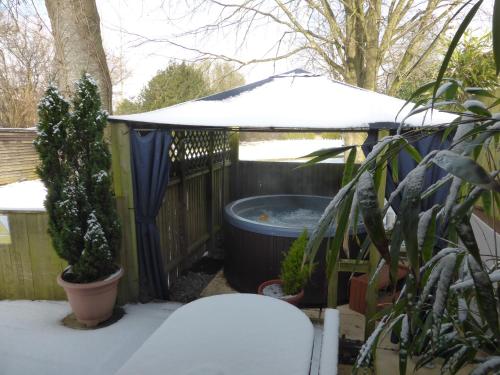 a hot tub in a gazebo with snow on it at Cypress Log Cabins Accommodation in Godshill