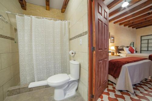 a bathroom with a toilet and a shower and a bed at Hotel Palacio Chico 1948 in Antigua Guatemala