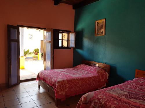 2 camas en una habitación con una pared verde en Hotel Lirice Colonial, en Comitán de Domínguez
