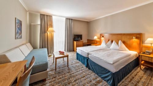 ein Hotelzimmer mit einem Bett und einem Sofa in der Unterkunft HOTEL POST alpine cityflair in Bruneck