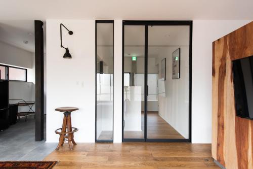 a glass pivot door in a room with a stool at Kamin Kanazawa in Kanazawa