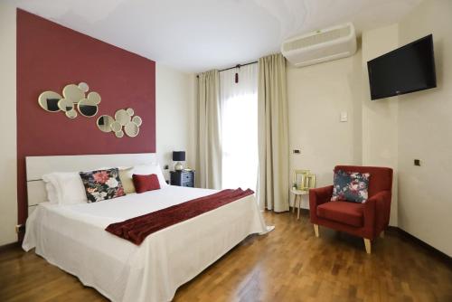 a bedroom with a large bed and a red chair at Pegasus Hotel in Sassari