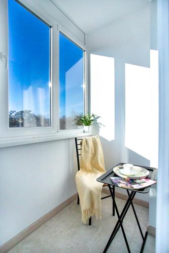 a table and a chair in a room with windows at Студия Luxury в центре in Mykolaiv